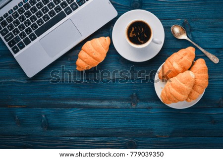Business breakfast, coffee and croissants, on a wooden surface. Top view. Free space for text.