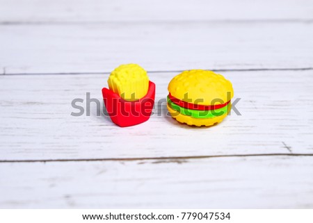 Concept of fast food of burger and french fries in kids eraser form on wooden background.
