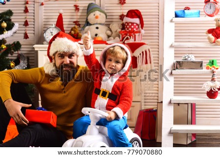 Happy family celebrate new year and Christmas. Father and child on car with new year present box. Xmas party celebration. Father and son in santa hat at Christmas tree. Winter holiday and boxing day.