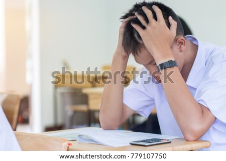 Asian boy student studying stressed headaches for test or exams in classroom, learning lessons doing final exam at high school with Thailand uniform in class room. Education system concept. Royalty-Free Stock Photo #779107750