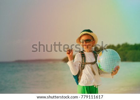 little boy with globe and toy plane travel on beach