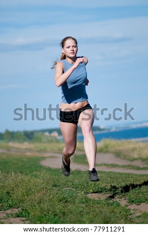 Beautiful teenage sport woman running in sea coast on sunny summer day