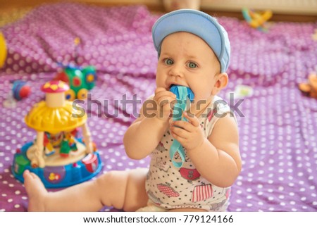 Baby girl in a blue hat in children's room playing with toys
