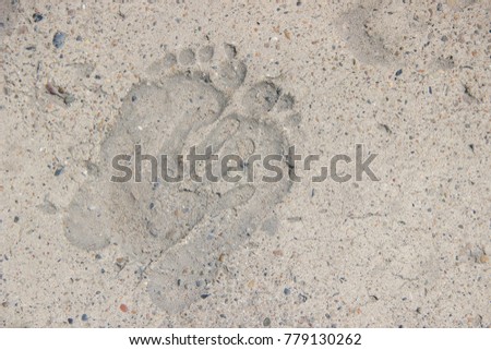 Traces of feet and palm of people on gray dry concrete in summer