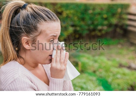 Attractive woman outdoor with tissue having allergy. Woman blowing her nose into tissue. young woman with handkerchief. Sick girl has runny nose. Female model makes a cure for the common cold 