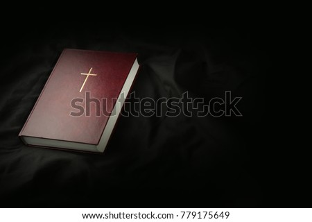 Bible on dark textile background. Holy Scripture with cross with copy space