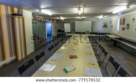 wooden conference table and chairs with office accessories. Papers, pens and books moving on the table. Whiteboard on background