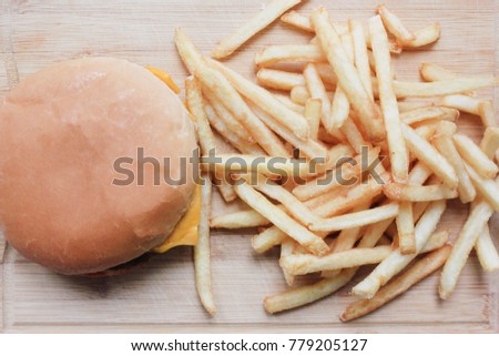 Fries and Burger Served on Wooden Board Platter in Fast Food Restaurant. Top View Image of Unhealthy Meal with Cheeseburger and French Fries in any Fast Food Chain. Burger Place Typical Meal Products.
