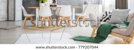 Open space living room with wooden table and white chairs standing in the dining area