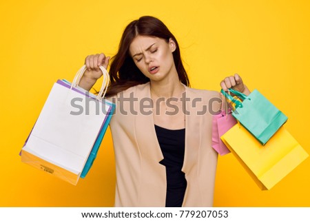 young beautiful woman with purchases on a yellow background                               