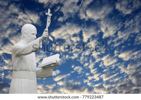 Saint statue against the blue sky in front of the public school, Thailand 