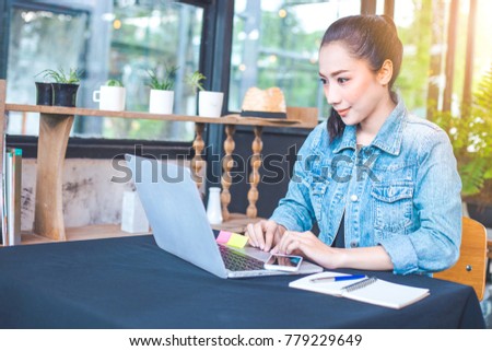 Woman works in a laptop computer in the office.On the table are mobile phones,notepad and pen.