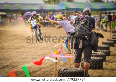 Sports photographers are shooting a Motocross race on a racetrack.