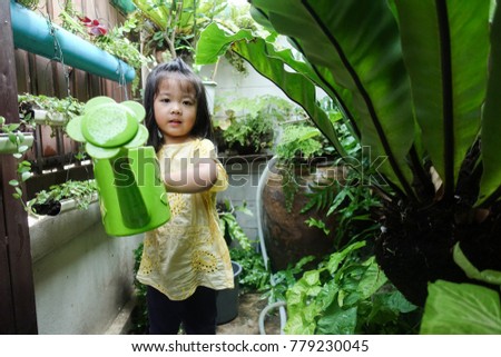 Little happy asian girl watering garden.