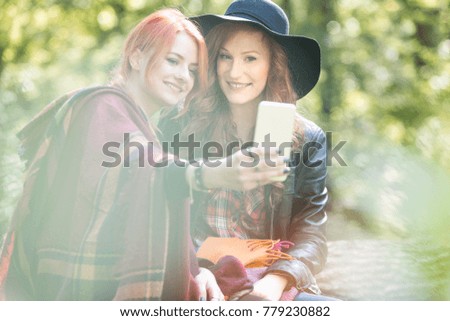 Smiling young girls wearing colorful fashionable clothes taking a photo in the park