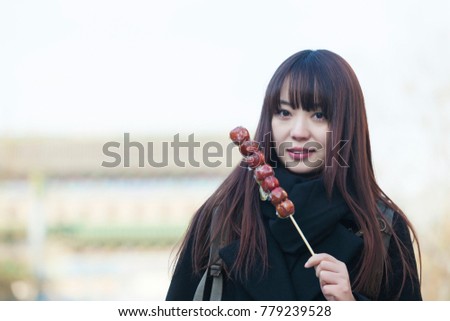 In Beijing, Dashanlan pedestrian street, the Chinese women eat Tomatoes on sticks