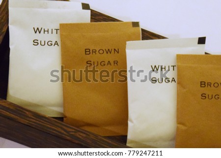 Sugar in a paper bag for tear On a brown and white rectangular wooden tray there is a white background. For refreshing drinks such as tea, coffee or cocoa for hotel guests, restaurants or cafes.