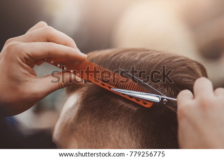 Close-up, master hairdresser does hairstyle and style with scissors and comb. Concept Barbershop. Royalty-Free Stock Photo #779256775