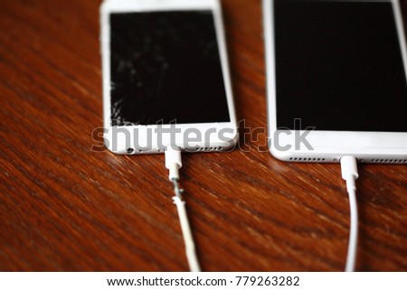 Old and new smartphone charge battery with new and torn wire, selective focus