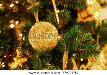 Concept New Year celebration background. Closeup photo of  christmas tree decorated with golden toys