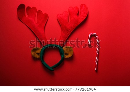 Christmas horns on a red table.Top view with copy space.Holiday background . Christmas and New Year Champagne.Christmas decoration. Funny Christmas antlers on red background.Pair of toy reindeer horn