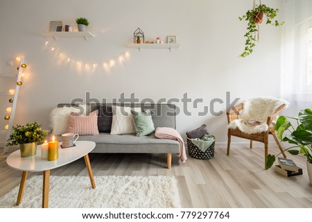 Sofa, coffee table and wicker chair in living room styled scandinavian Royalty-Free Stock Photo #779297764