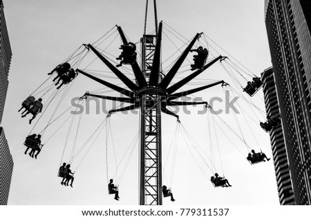 Black and white spinning ride with buildings at the side