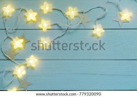Star twinkle lights on a blue wooden background.