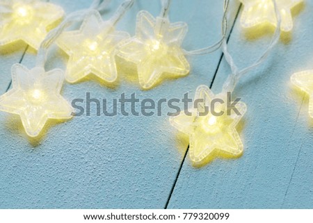 Star twinkle lights covered with frost on a blue wooden background