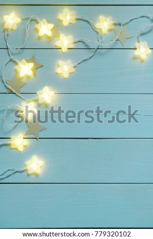 Star twinkle lights on a blue wooden background.