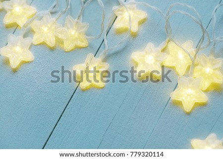 Star twinkle lights covered with frost on a blue wooden background
