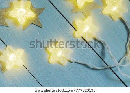 Gleam of star twinkle lights covered with frost on a blue wooden background, closeup.