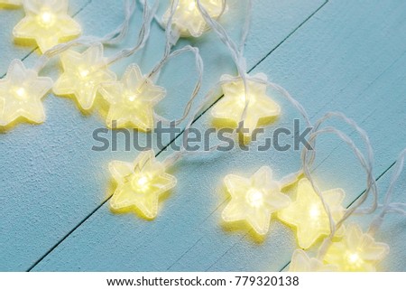 Gleam of star twinkle lights covered with frost  on a blue wooden background.