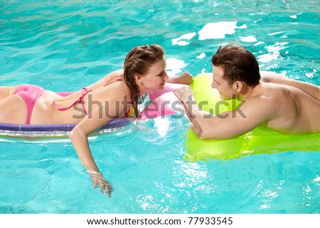 Handsome guy and pretty girl looking at one another in swimming pool