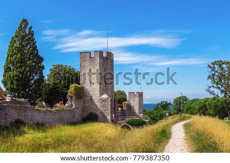 The defensive wall of Visby, Gotland in Sweden. The strongest and best preserved medieval city wall in Scandinavia. Beautiful view. Angular watchtowers and footpath along them. Blue sea on background. Royalty-Free Stock Photo #779387350