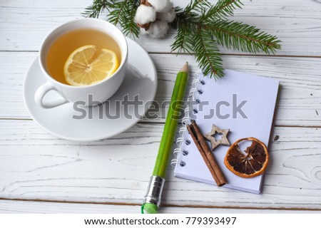 A festive winter mock up photo with a cup of tea, fir twigs, an opened note book, a pencil and decoration elements
