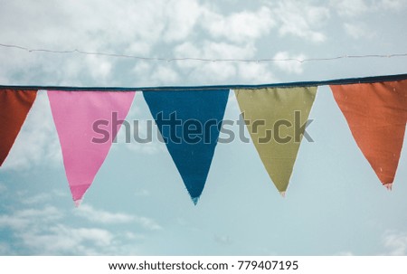 Colorful bunting hung up outside against a blue cloudy sky