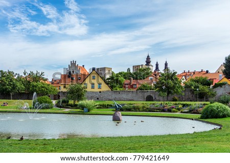 Park Almedalen in Visby, the main city on island Gotland, Sweden. The best-preserved historical medieval city in Scandinavia. Beautiful view with color old buildings, lake, resting or relaxing people. Royalty-Free Stock Photo #779421649