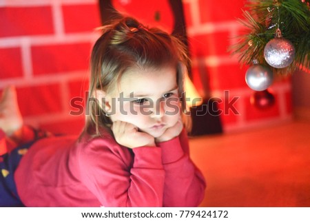 Beautiful little girl with decorations for Christmas evening. Cute little girl portrait in front of Christmas tree