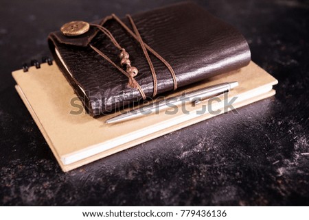 Vintage aged notebook on a diary next to a pencil on a dark board