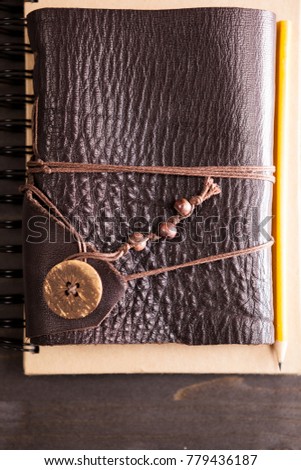 Pencil on retro notebook with leather cover on wooden backgorund