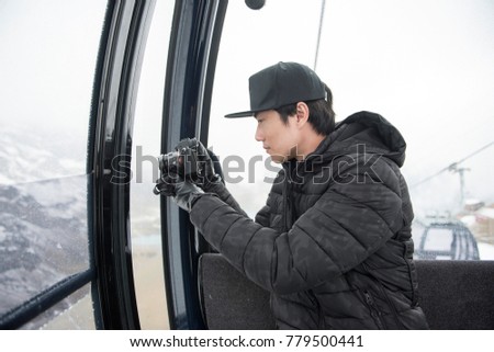 asian man using his camera while sit in cable car