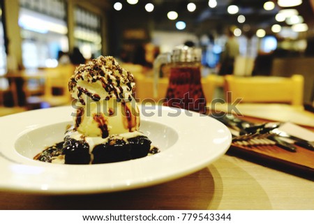 Chocolate mud brownie and vanilla ice cream with whipped cream on white plate at dessert shop. Delicious dessert with space for text. Concept be used for bakery and coffee shop business. Blur picture.
