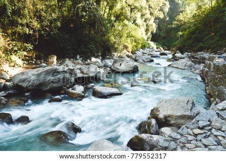 Wild mountain river with huge boulders in Himalayas, Nepal. Long shutter speed. 