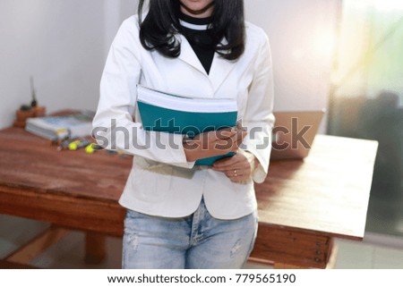 young woman  reading a book and laptop computer on wood desk at home