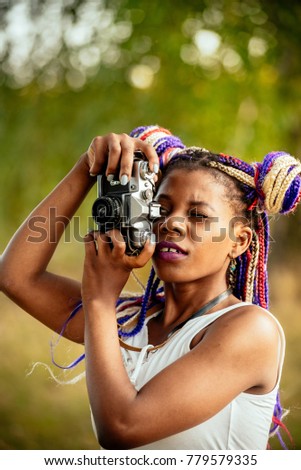 happy young african american female photographer looking to vintage camera