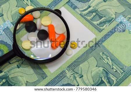 magnifying glass on medication with uncirculated iraqi dinar (IQD) isolated on white