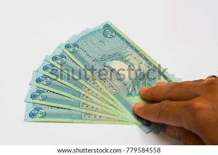 hand holding uncirculated iraqi dinar (IQD) isolated on white