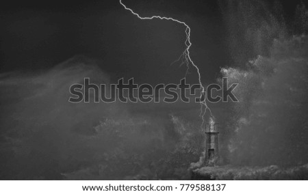 Lightning and wave over old lighthouse and pier of Viavelez in Asturias, Spain.
