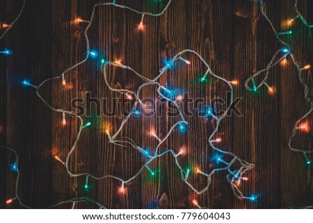 Fancy blinker light bulbs or garlands and wreath on wood table for Christmas or New years decoration background, space for add text or picture.